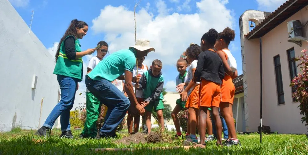 Crianças ajudam no plantio de mudas de árvores em escola municipal